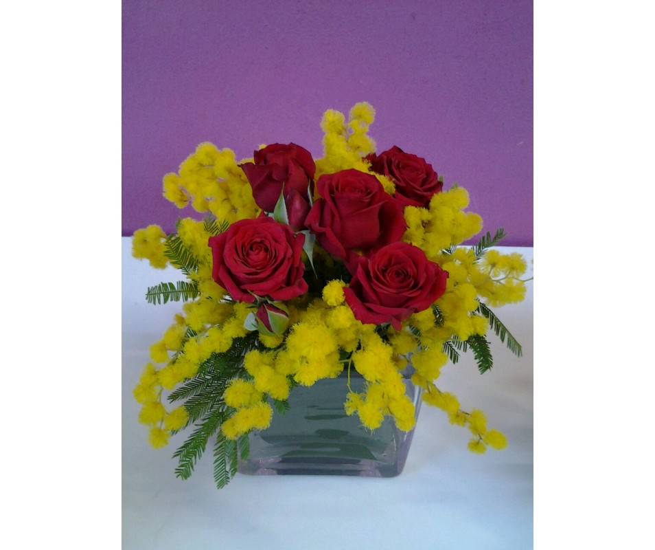 Mimose e roselline rosse in vaso di vetro